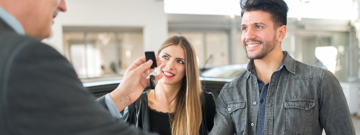 Male and female being handed keys by a CDJR dealer