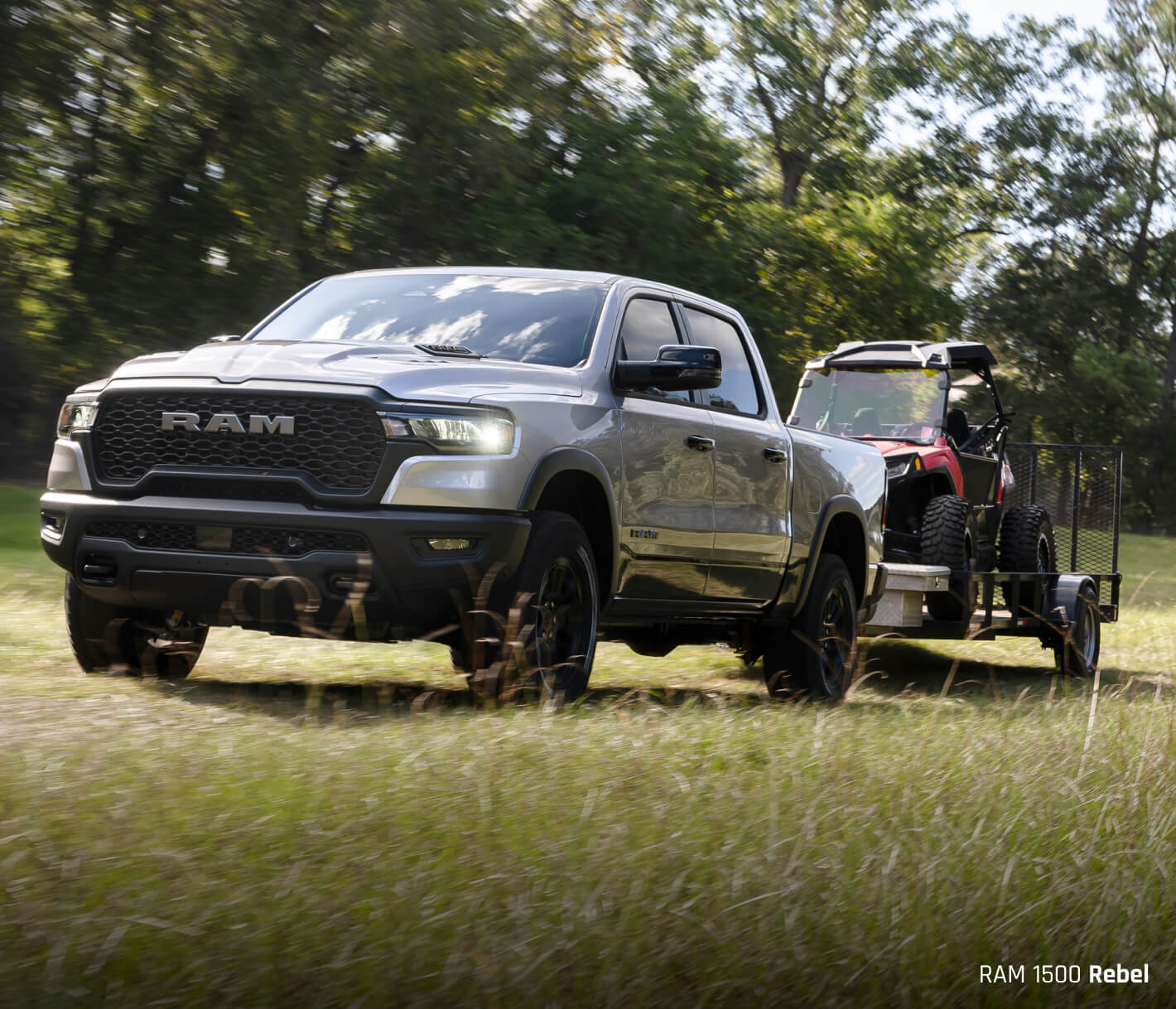 Gray Ram 1500 towing a trailer with lawn machinery in it